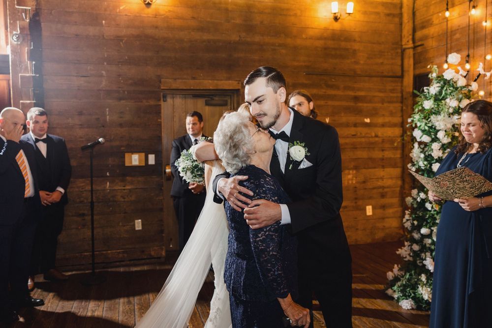 A romantic first dance moment at a rustic barn wedding venue with wooden walls and decorative holiday lights.