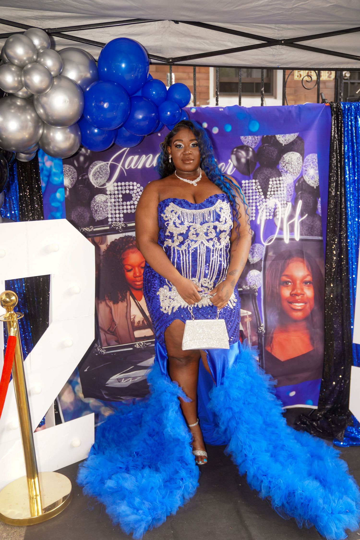 Elegant party setup with blue and silver balloons, decorative backdrop and flowing blue tulle decorations at a celebration.