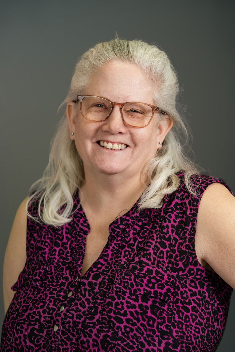 A series of five similar photos showing someone in a pink and black patterned sleeveless top against a gray background.