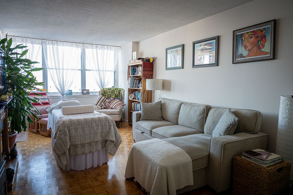 Cozy living room interior with beige furniture, hardwood floors, framed artwork and a Christmas tree by the window.