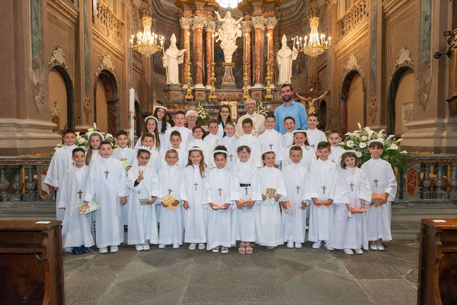 Large group of altar servers in white robes posed in ornate church sanctuary.