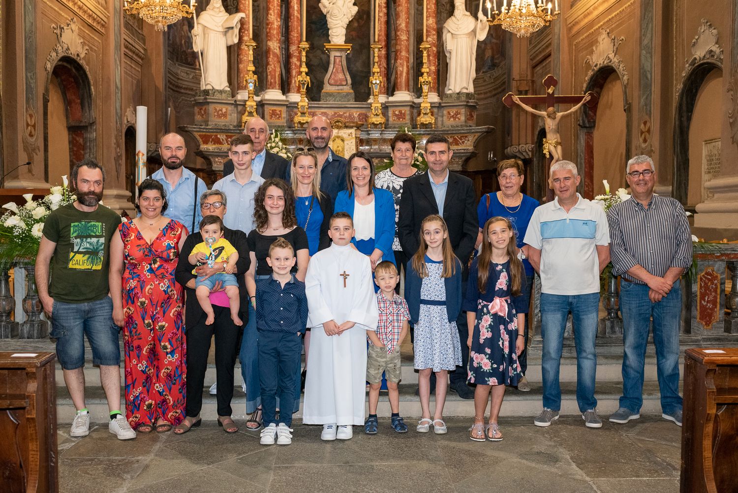 Family group photo with altar server in white robes inside decorated church sanctuary.