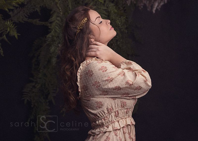 Maternity photo session in a forest setting with soft lighting and a flowing cream-colored lace dress.