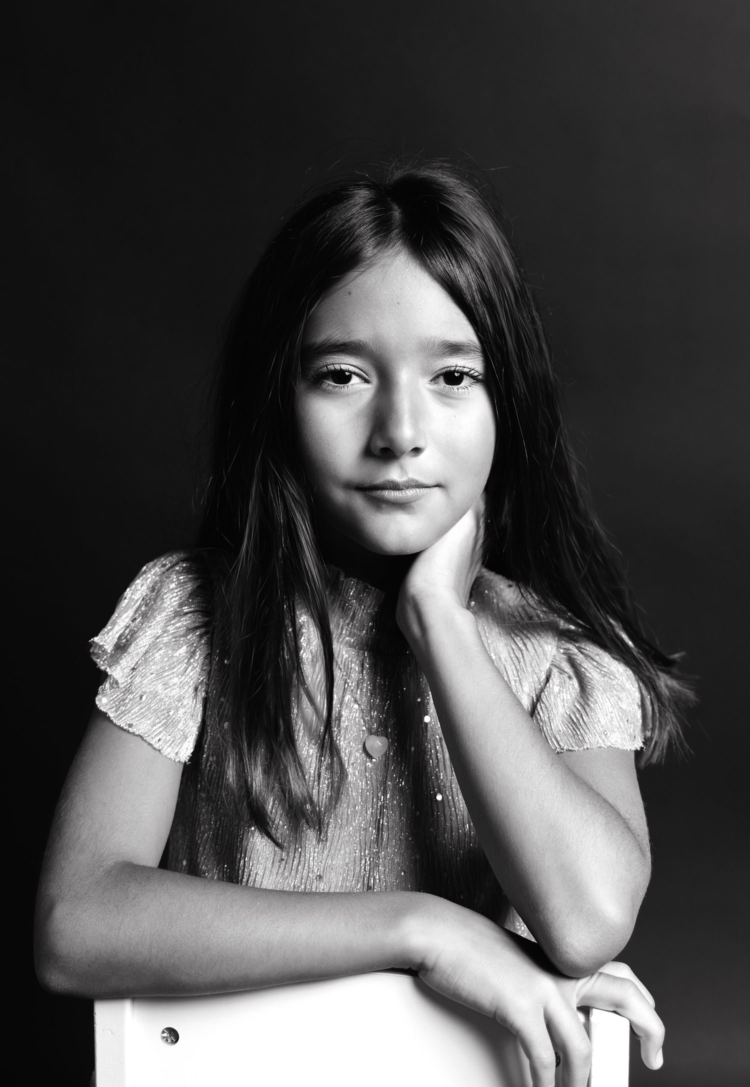 A series of black and white portraits showing someone in a white top posing expressively against a dark background.