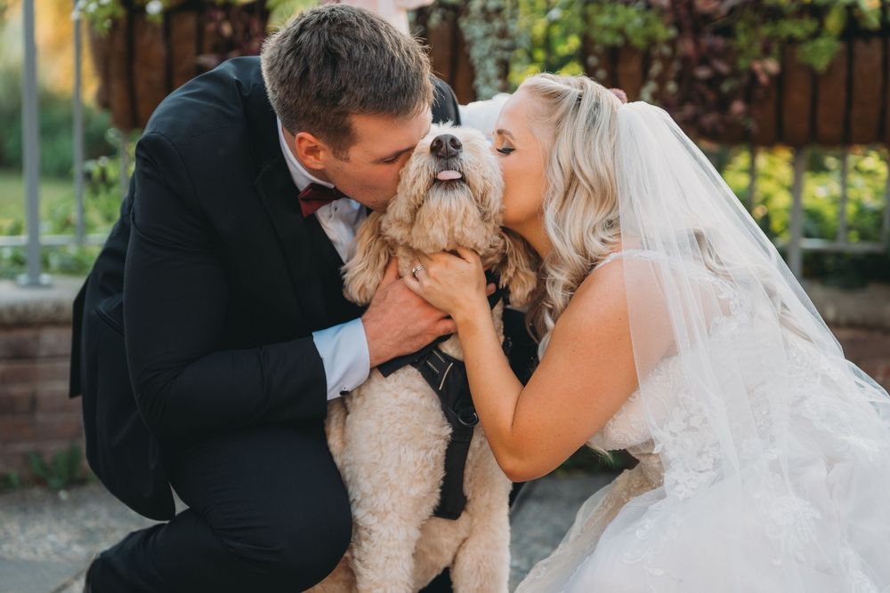Romantic newlywed couple shares a tender kiss during their outdoor garden wedding ceremony.
