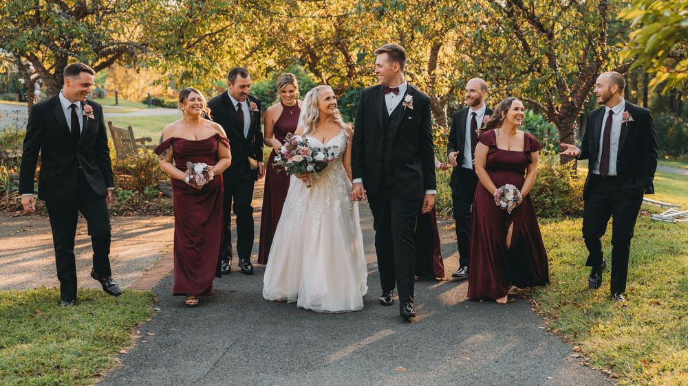 Wedding party gathers outdoors in autumn with golden foliage and warm sunlight creating a scenic backdrop at the Atrium at Meadowlark