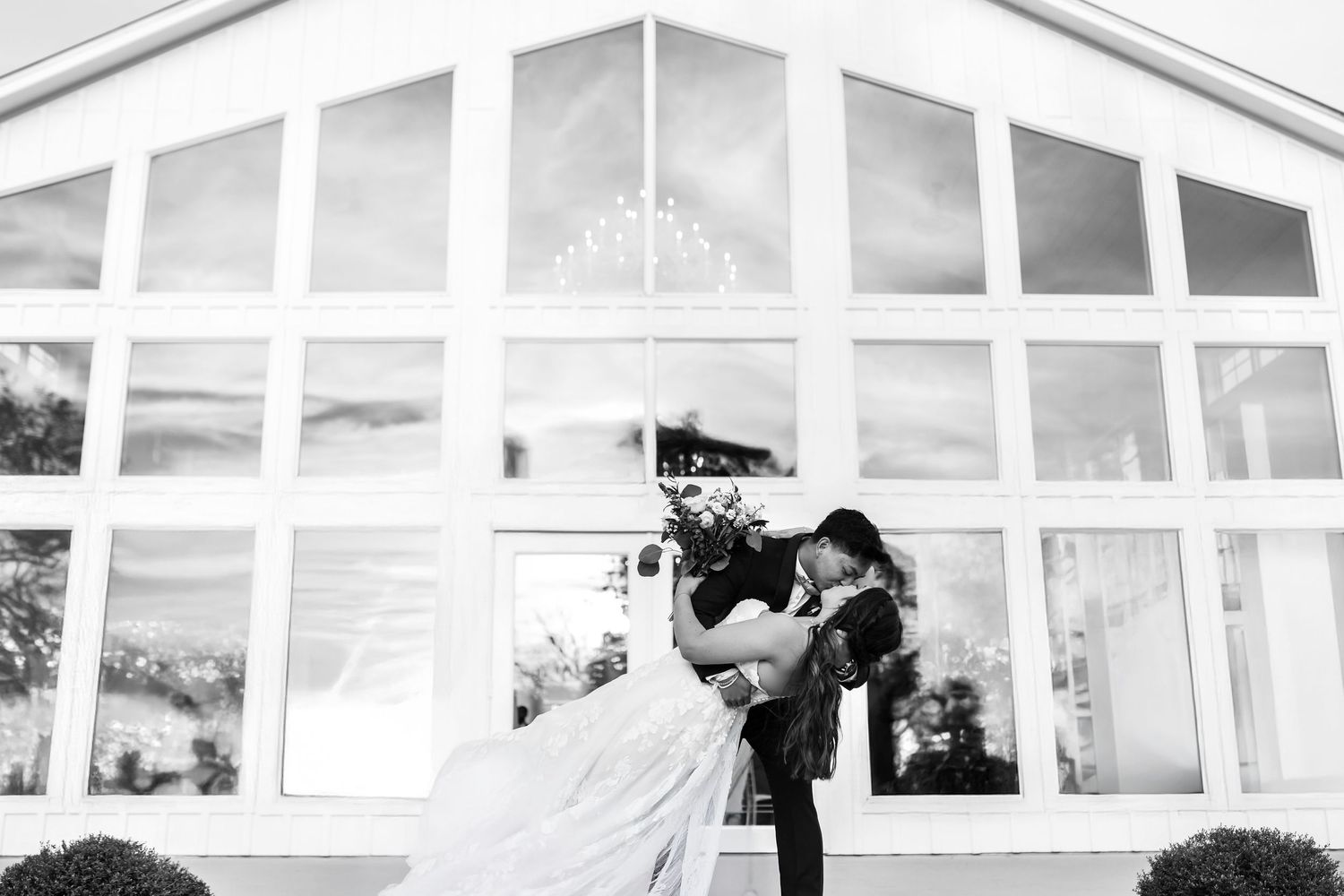 Elegant black tie couple portrait in natural spring light dipping and kissing