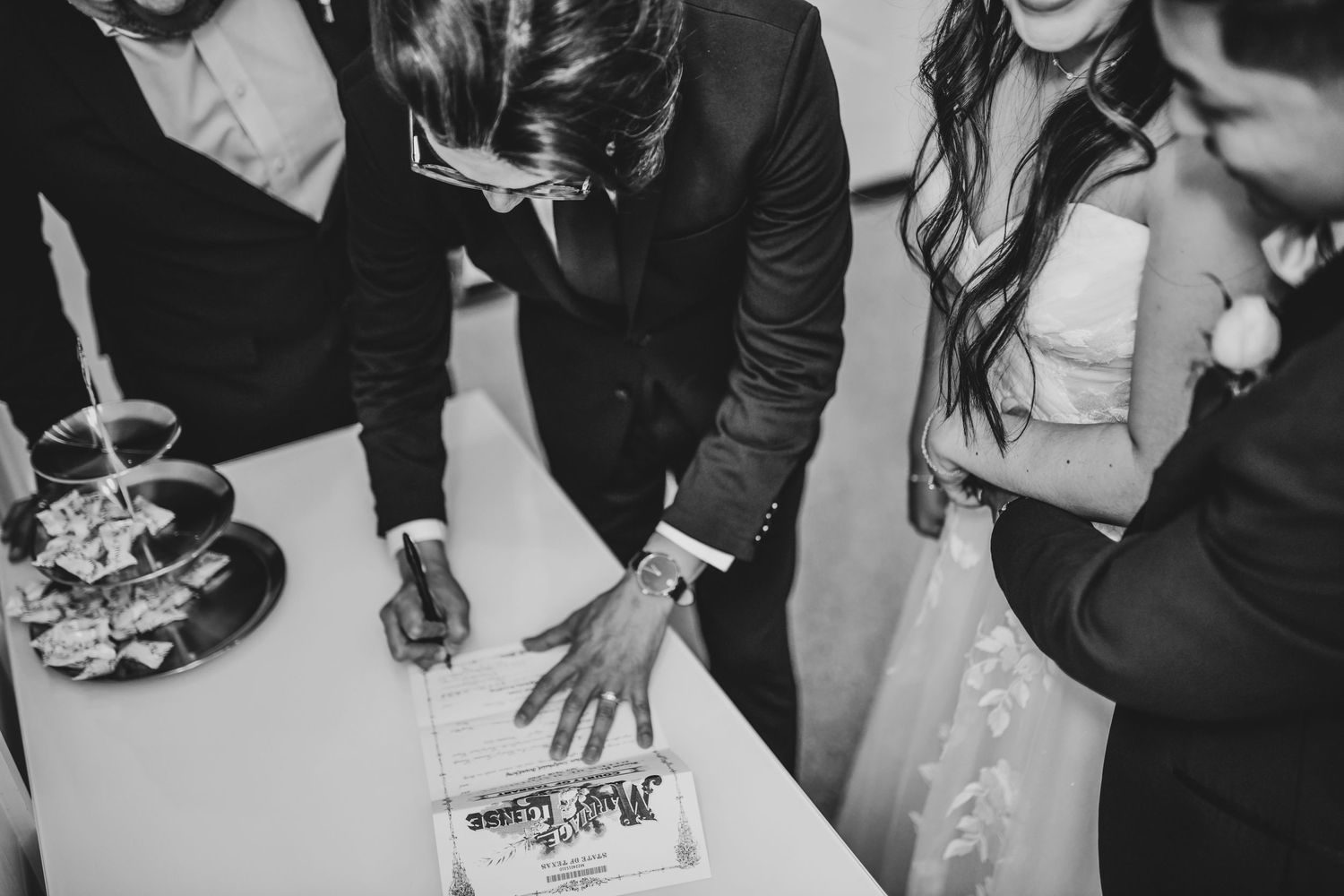 sentimental moment of officiant signing the marriage license as the bride and groom laugh