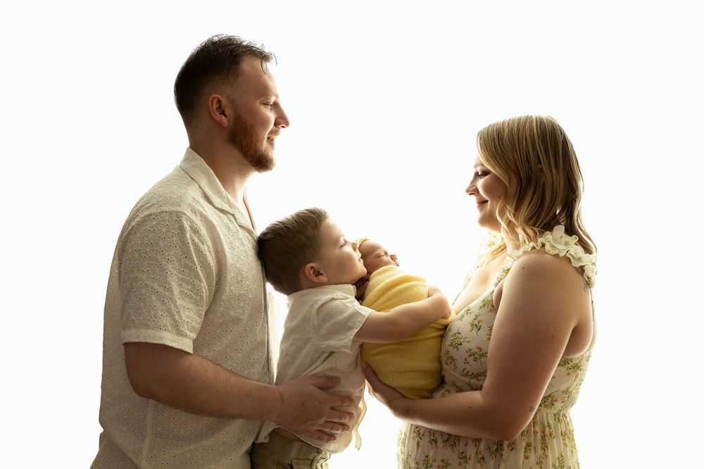 A loving family silhouetted against bright sunlight shares a tender moment together.