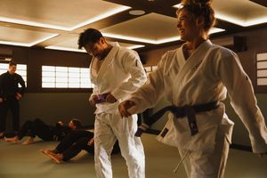 Martial arts practitioners in white uniforms demonstrating self-defense moves during training.