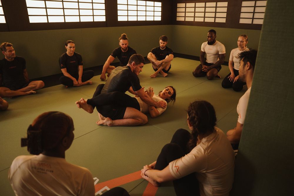 Students practicing martial arts techniques while lying on mats in a traditional dojo setting.