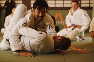 Students practice martial arts techniques on training mats in a traditional dojo setting.