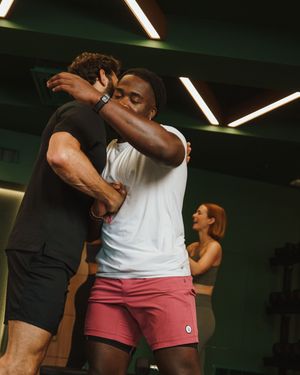 Athletes practicing grappling techniques in a modern gym setting with geometric lighting.