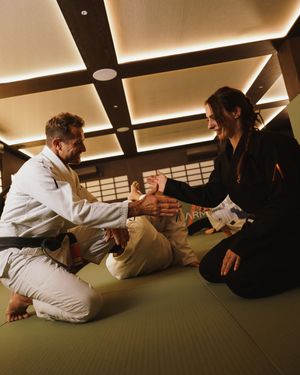 Martial artists practicing grappling techniques on a traditional tatami mat floor in a dojo.