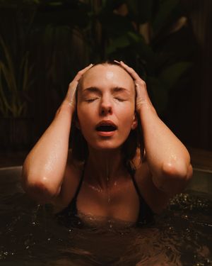 Close-up sequence showing a person emerging from dark water with closed eyes and wet hair.