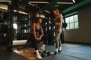 Fitness training session with people exercising on mats in a modern gym studio.