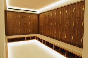 Modern locker room interior with wooden lockers and LED lighting along the ceiling.
