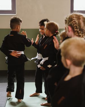 Students in black martial arts uniforms practicing techniques during a training session.