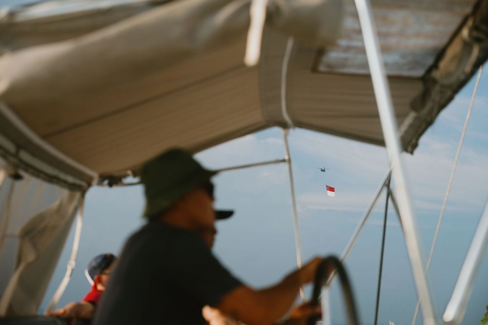 People fishing from a boat deck on calm waters during a sunny day.