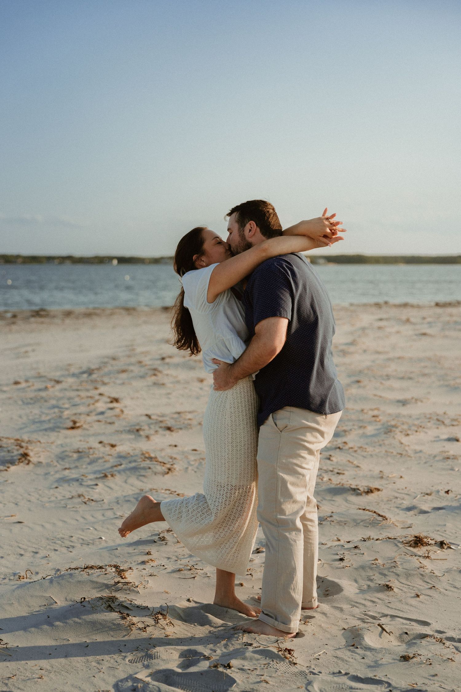 A romantic dance sequence on a sandy beach during sunset.