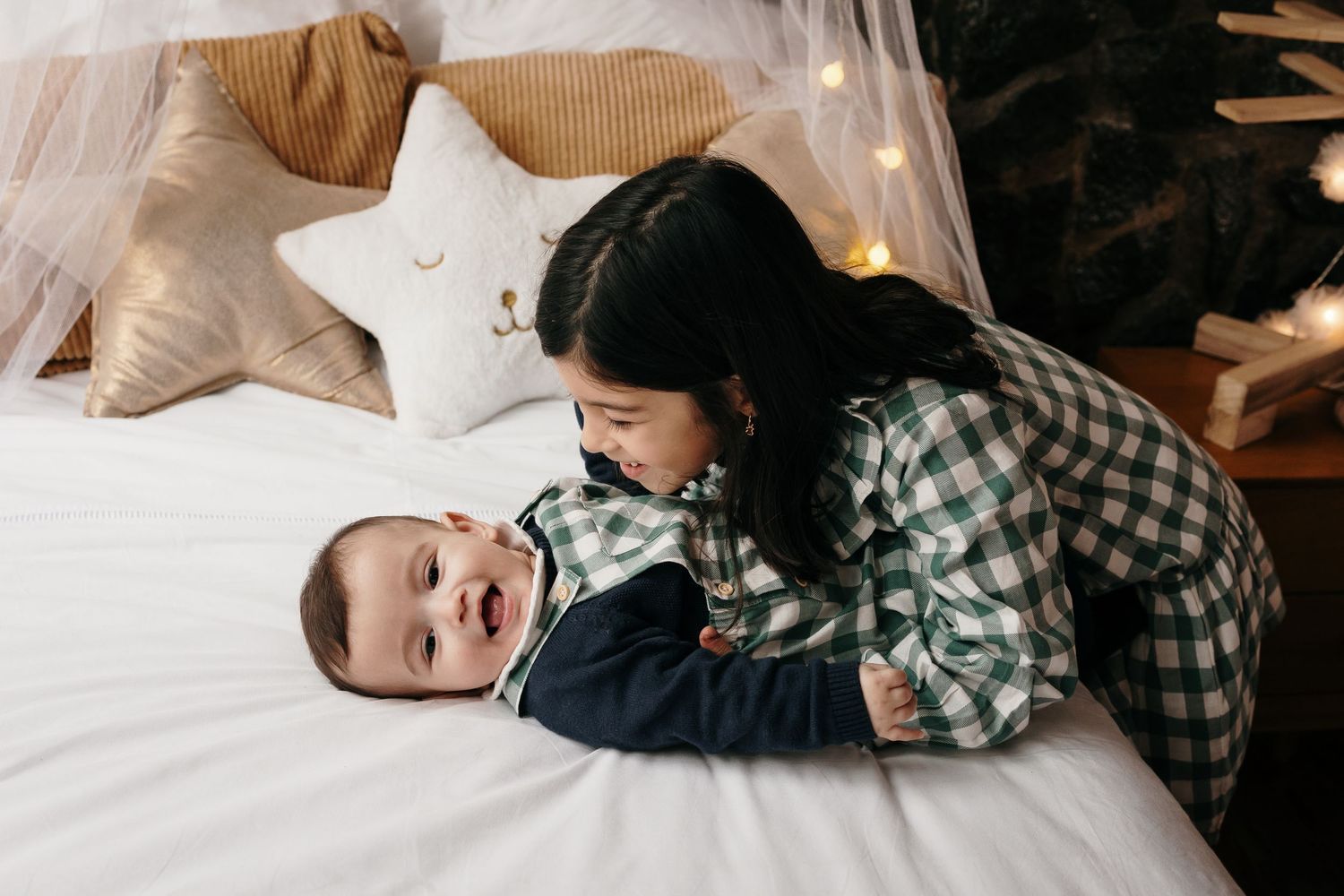 Family cuddles together on white bedding during lifestyle photo session.
