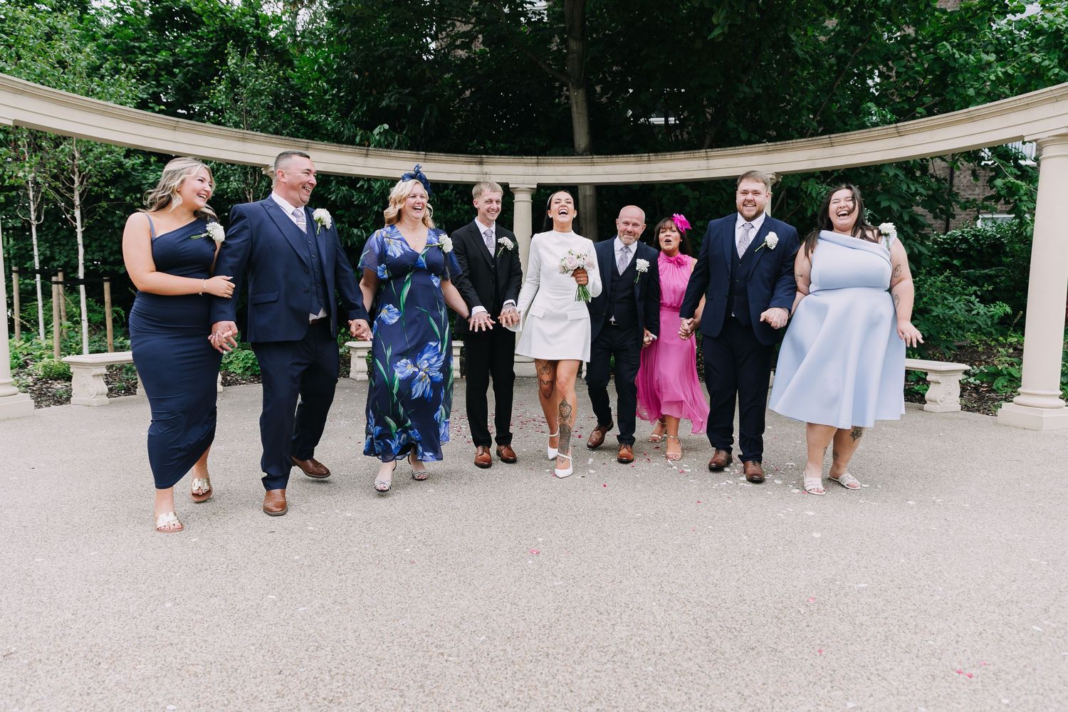Wide shot of wedding guests lined up under a white pergola in a garden setting. Photographer. Hull. East Yorkshire. Photography