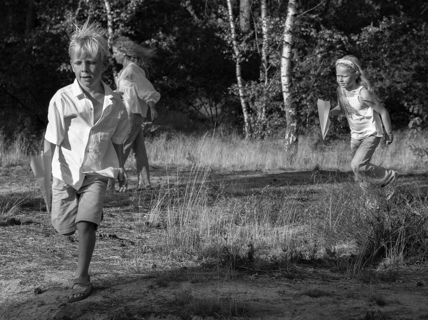 Panoramic series of people walking through a wooded area in black and white.