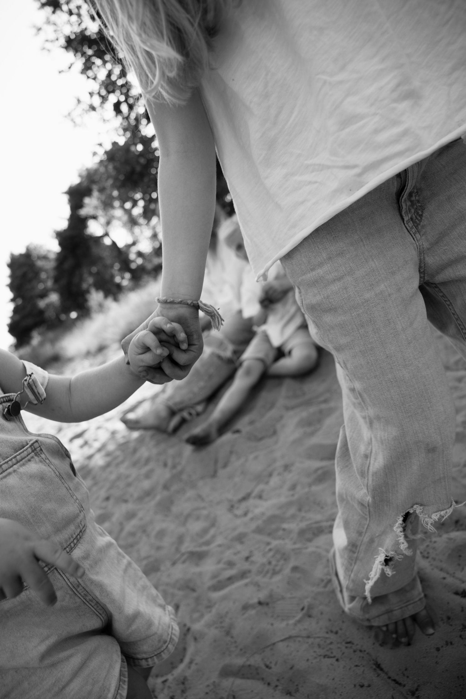 Close-up black and white shots of hands playing in beach sand.