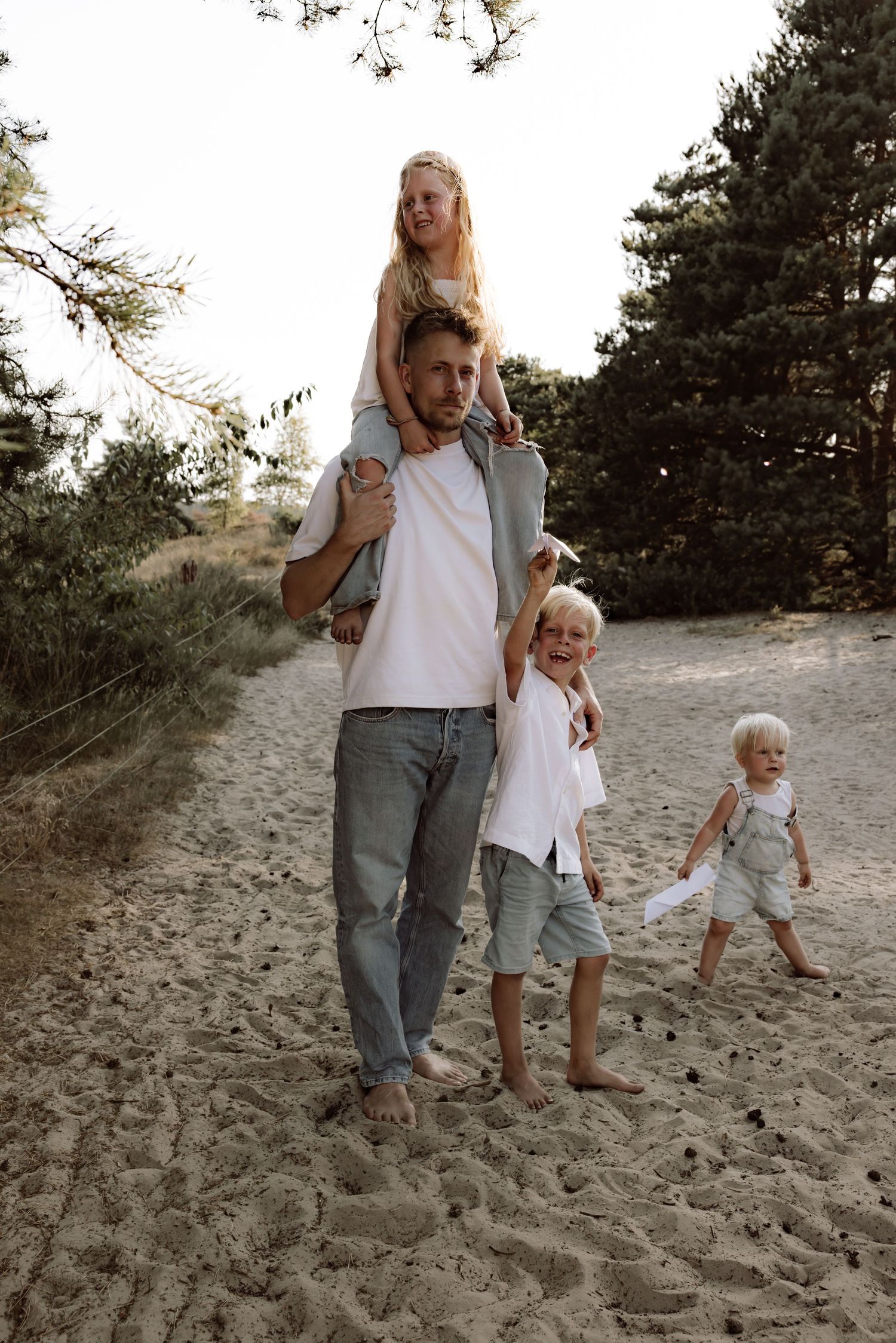 Family walking together on sandy dunes during golden hour.