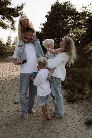 Playful family interaction on sandy beach during sunset photoshoot.