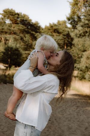 Joyful parent lifting child in air against natural outdoor backdrop.