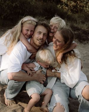 Family sharing intimate group hug on sandy beach during sunset.