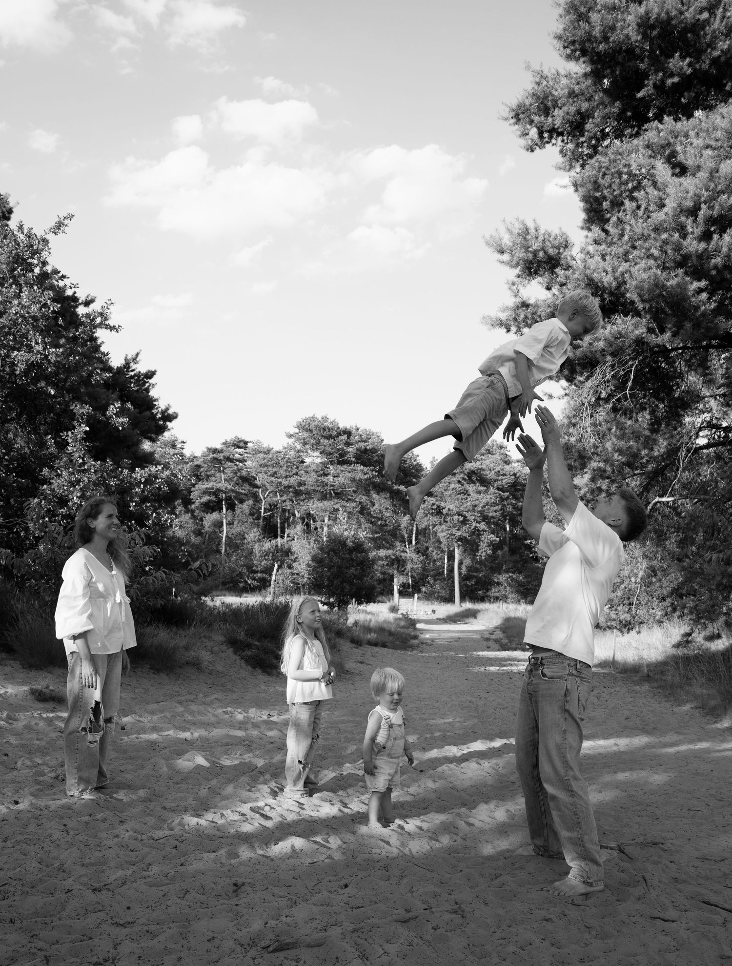 Family enjoying outdoor playtime together in a natural setting with trees in the background.