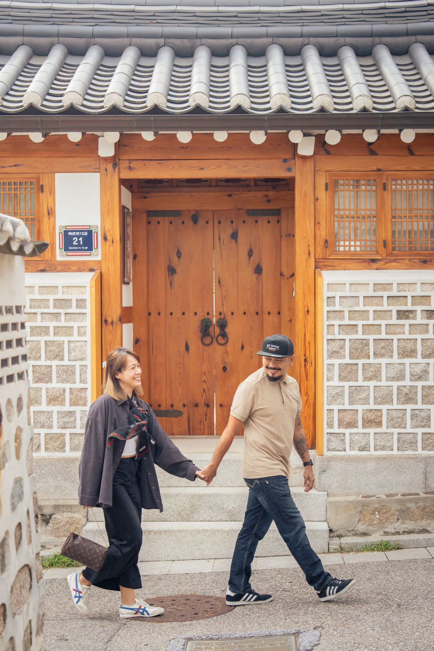A sequence of photos showing playful interactions between people along a traditional Korean hanok wall and doorway.