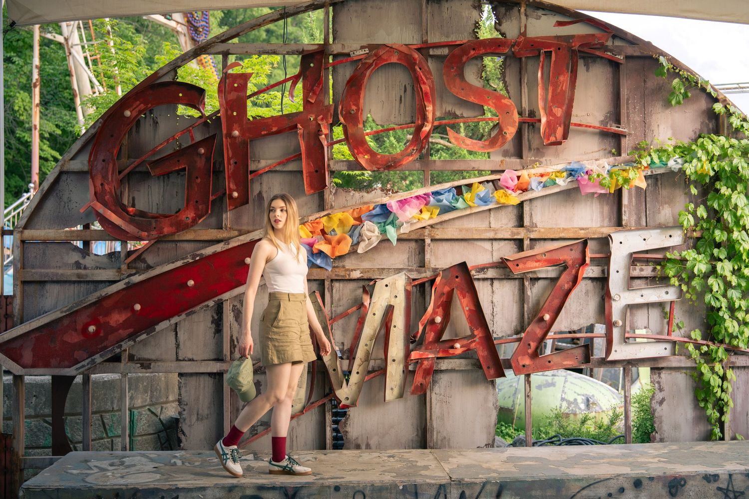 A rustic wooden wall displays a vintage-style 'GHOST WALK' sign decorated with colorful lights and spooky ambiance.
