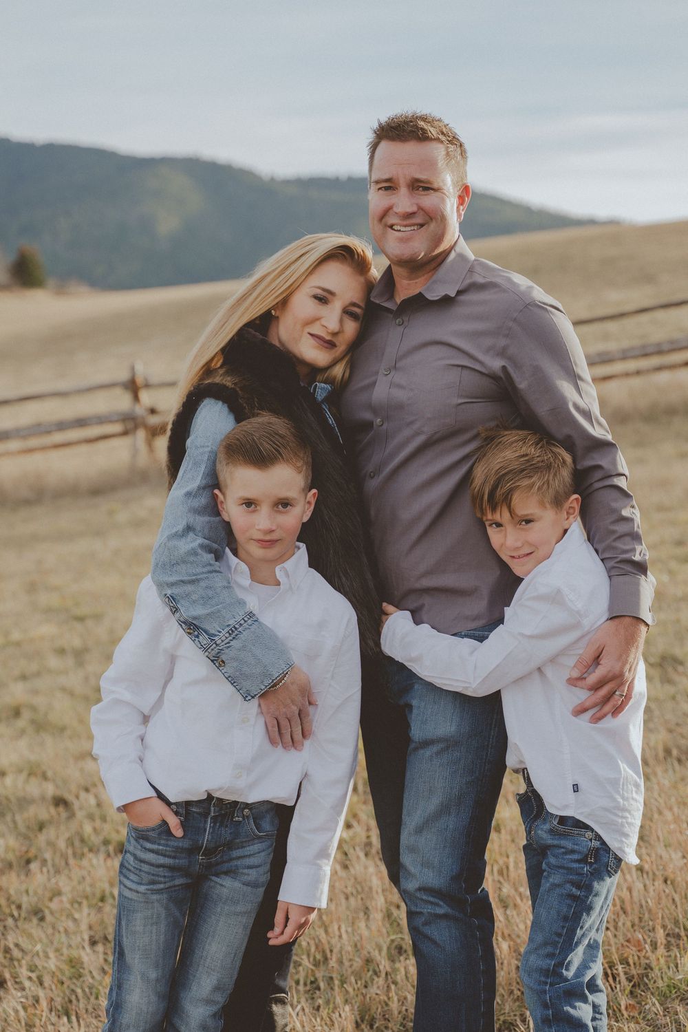 Casual family portrait in an autumn field with mountains in the background.