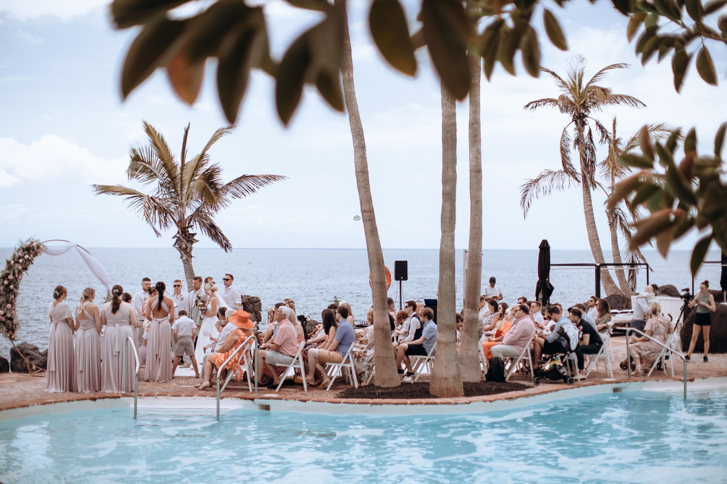 Tropical beach wedding ceremony setup with palm trees and turquoise ocean views.