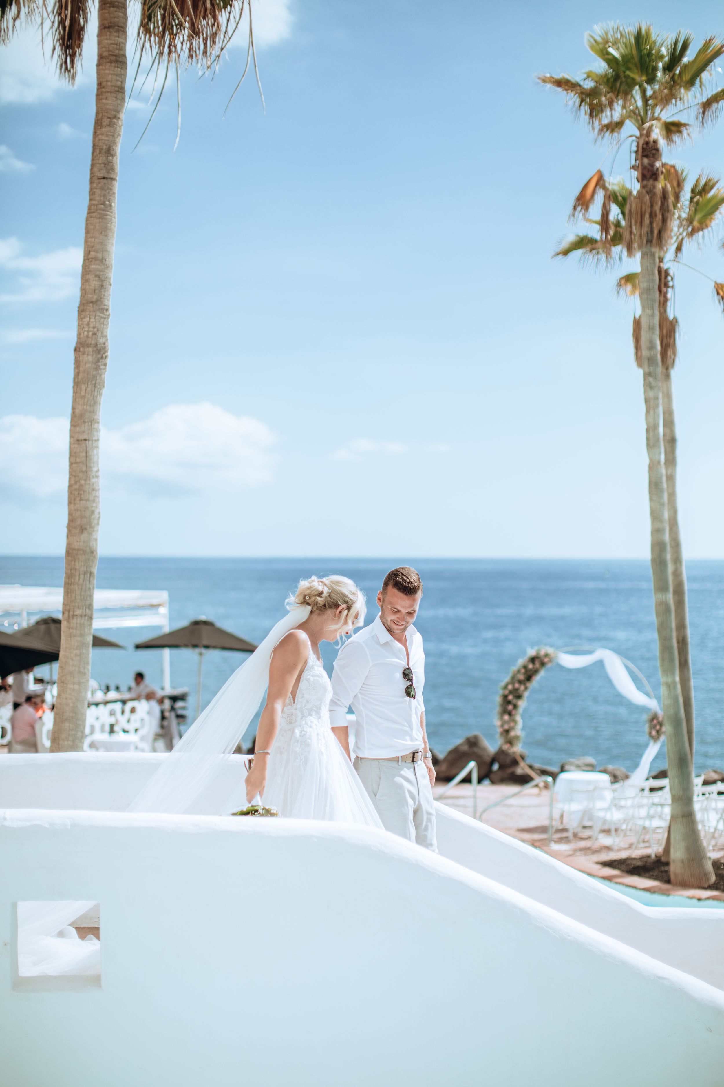 Destination wedding setting with ocean views and palm trees against bright blue sky.