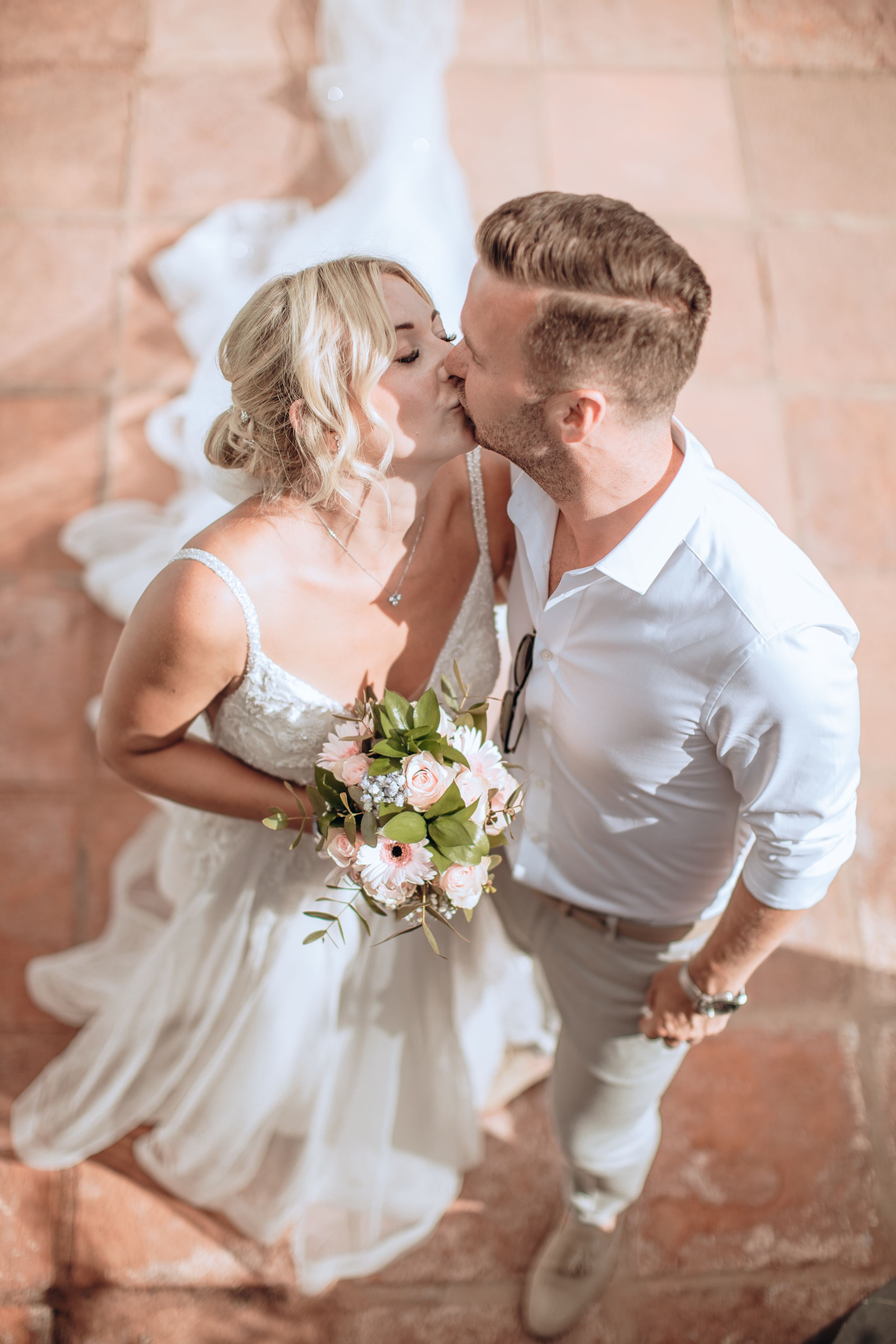 Romantic wedding couple sharing a tender moment as the bride holds a delicate bouquet of white flowers.