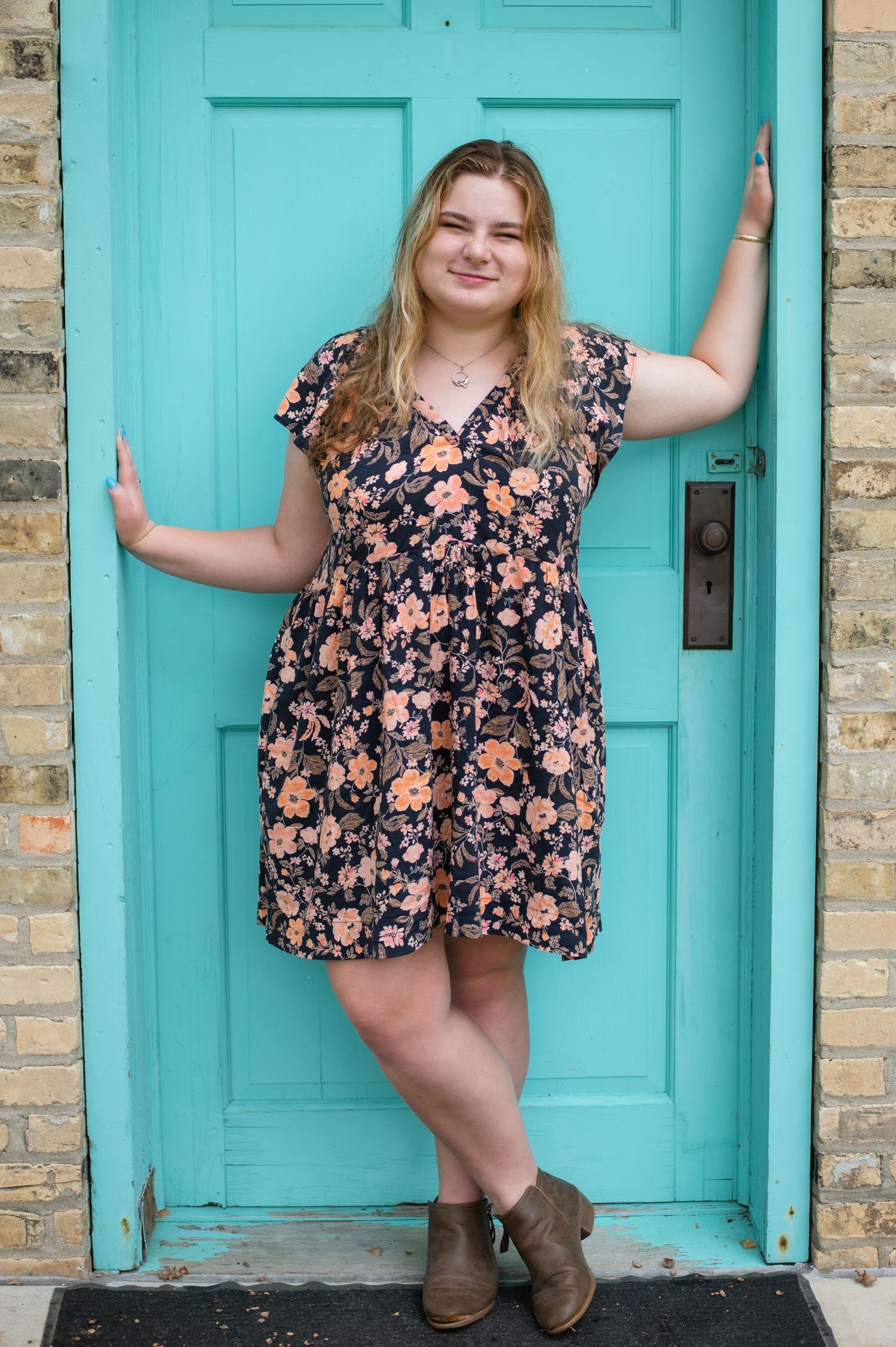A person in a floral dress and brown boots poses on a white wooden bridge walkway in three different stances.