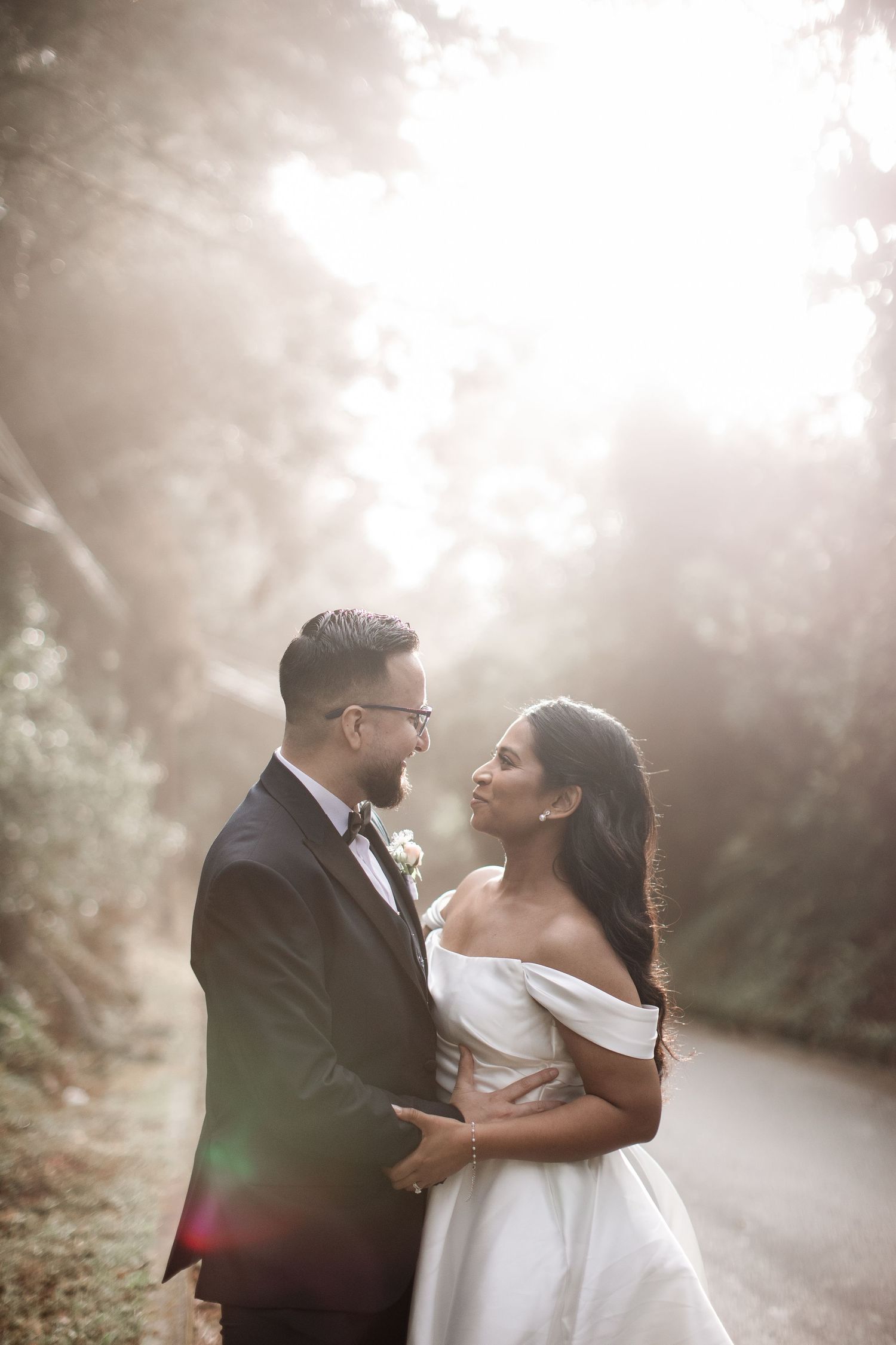 Elegant bridal portrait with delicate lace dress and floral bouquet against neutral background.