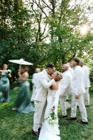 Dynamic motion blur shot of wedding guests dancing in white attire outdoors.