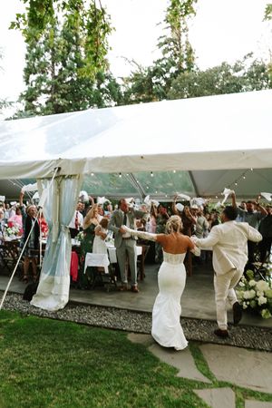 Wedding celebration under a white tent with guests dancing and enjoying the festivities.