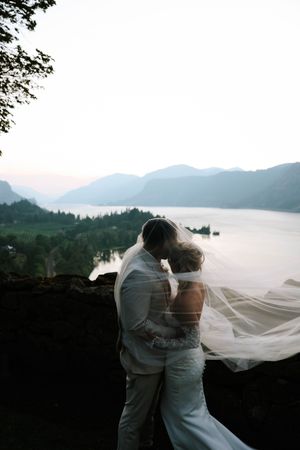 Romantic wedding moment overlooking a misty mountain lake at sunset.