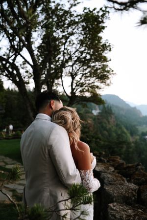 Romantic wedding portrait overlooking scenic mountain valley with dramatic landscape.