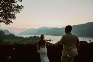 Couple embraces against a scenic mountain landscape during golden hour.
