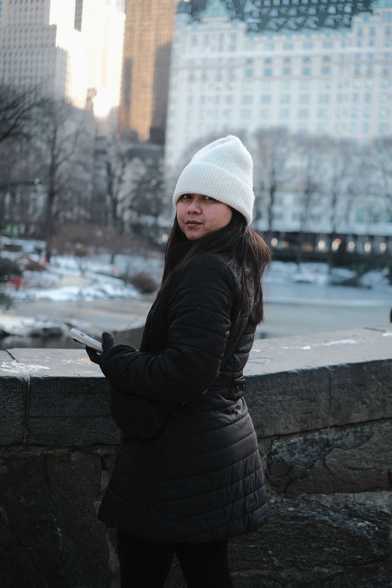Winter scene in an urban park with snow and skyscrapers in the background.