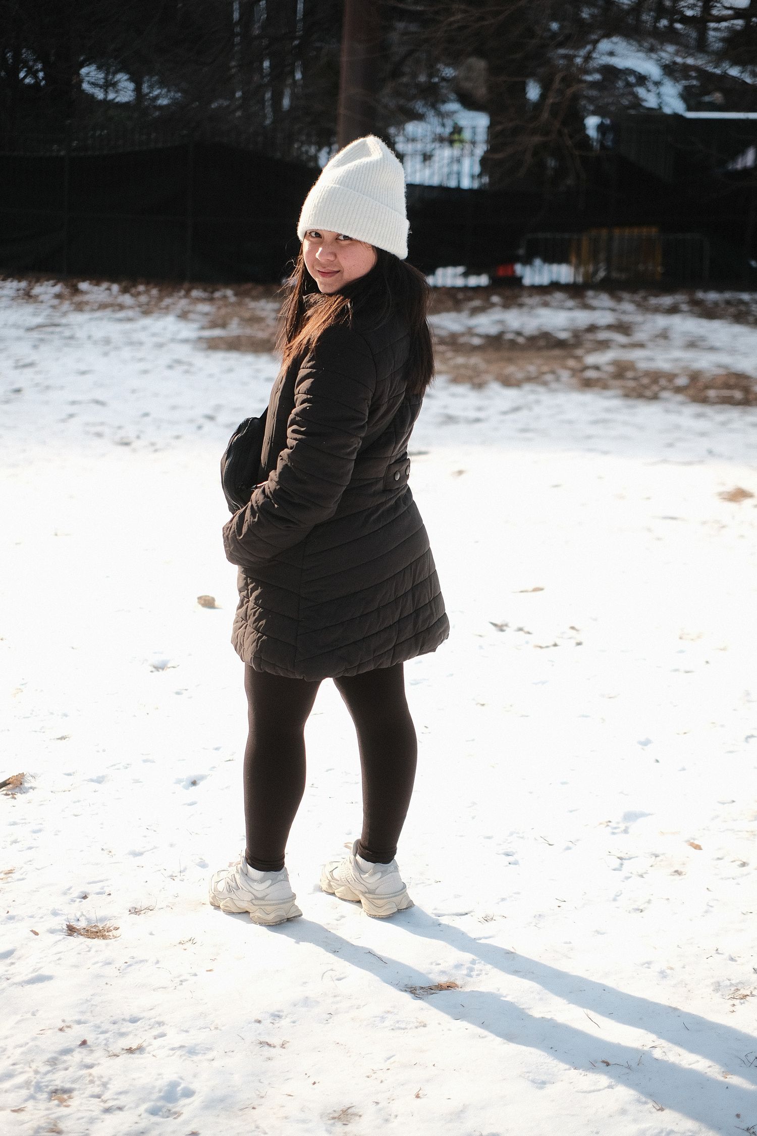 Figure in winter clothing casting long shadows on snowy ground.