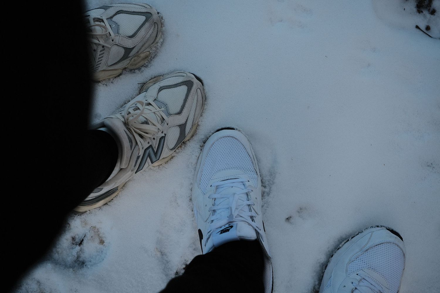 Footprints and patterns in fresh snow against a light blue background.