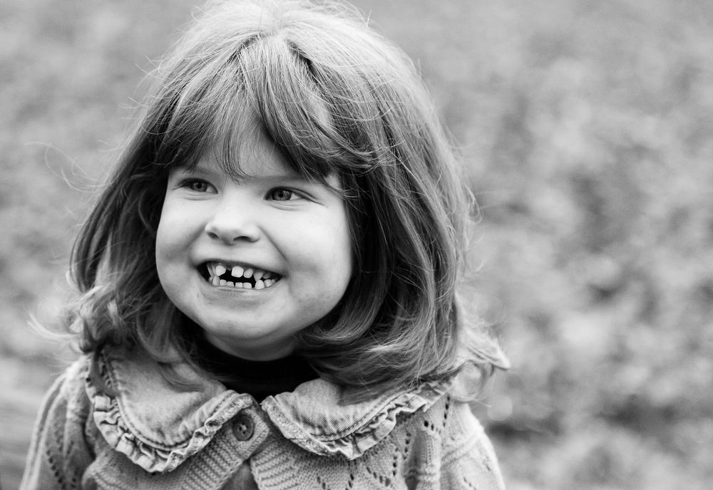 A series of black and white portrait photos showing a smiling child with a playful expression.